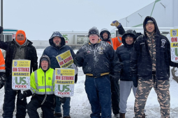 A group of workers stands in the snow and cold outside a US Foods yard in Spokane, Washington holding signs that say Local 705 Teamsters On Strike Against US Foods.