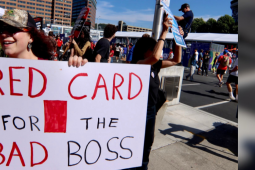 A worker holding a sign that says: Red card for the bad boss