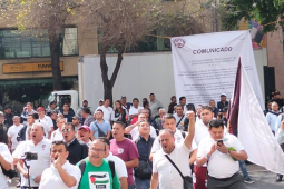 Workers gather with fists in the air and the union's flag flying behind them. 