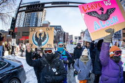 Marchers bundled against the cold carry colorful signs