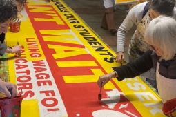 Several people paint a big banner that says ‘We Can’t Wait.’