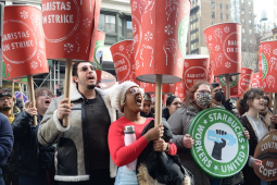 A crowd raise huge red cups that say “Baristas on Strike”