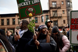 A group rallies holding signs that say Red Cup Rebellion: Unfair Labor Practice Strike, with a Starbucks coffee cup with a red line through it.