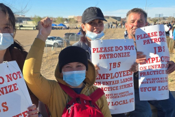 Four strikers holding signs, one with a fist in the air, face the camera.