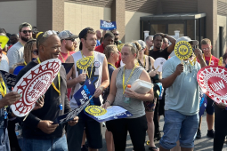 A crowd with UAW signs gathers outside a union hall for a rally.