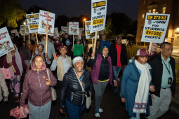 East African workers carrying signs march in the dark during the strike.