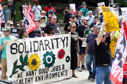 A rally with 30 or so people with a mixture of colorful signs, including Painters Union and a “We Want Good Jobs and Health Environments” banner