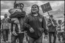 Lelo Juarez stands with his wife and child at a May Day march. Behind him, someone holds a sign reading "without fear" in Spanish. 