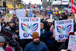 Mass march with many handmade anti-ICE signs. Most prominent are rainbow butterflies with the word "Together." Another in lower right says "How do have money for ICE but not teachers, veterans, childcare, health care, mental heath services, clean water, SNAP?" A flag farther back in crowd shows Star Wars rebellion logo.
