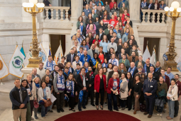 Fifty people pose on the stairs inside the Rhode Island capitol.