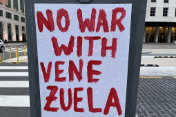 A handpainted sign on a city street reads in red letters "no war with Venezuela."
