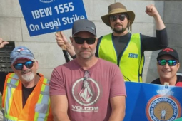 Five men in hats, sunglasses and hi-viz vests hold signs--including one that says IBEW 1555 On Legal Strike