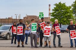GM strikers picketing on the road holding signs.