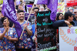 Workers rally holding colorful banners and signs.