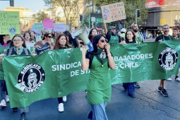 Workers in green aprons march behind a union banner.