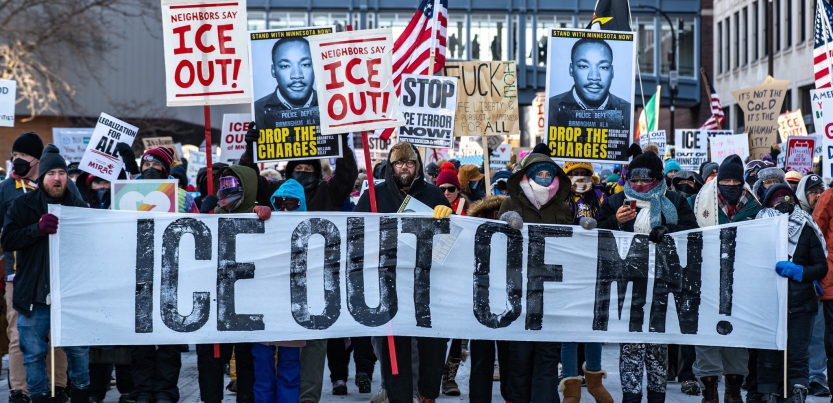 A big crowd carries a banner “ICE out of MN!”