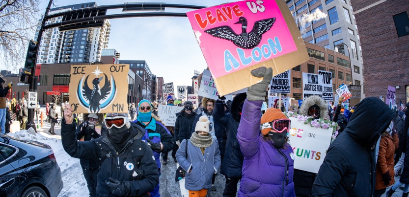 Marchers bundled against the cold carry colorful signs