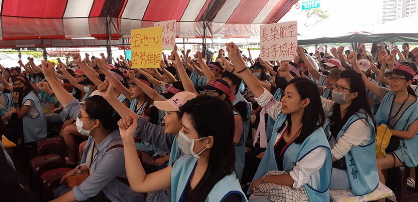Taiwanese flight staff assembled in protest with arms raised.