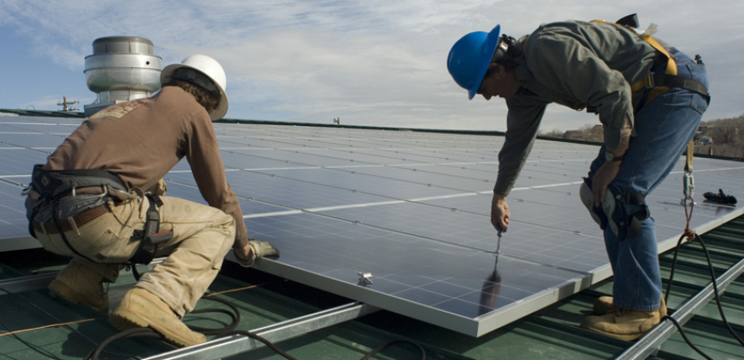 Two workers installing solar energy at Garfield County Fairgrounds