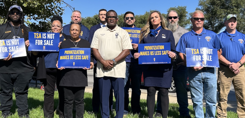 A group stands with signs against privatization of airport security