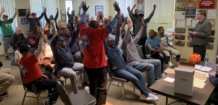 Strike authorization vote - people standing with arms raised.
