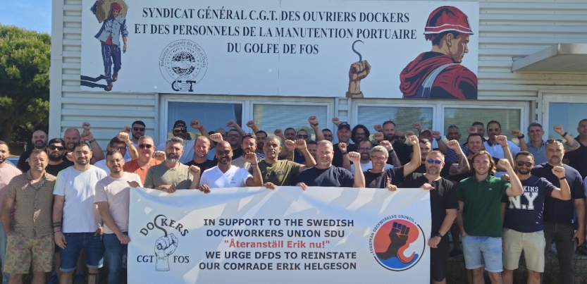 A group of workers hold a banner in front of a French banner. 