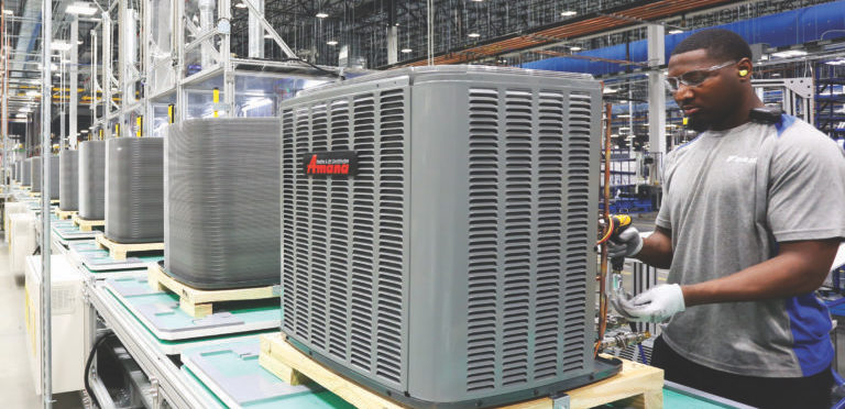 A worker at an Asana heat pump assembly factory stands with a drill working on a heat pump