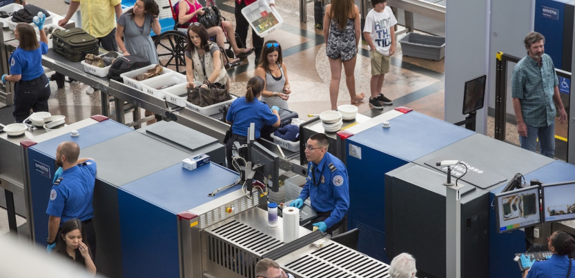 TSA workers are shown screening bags and scanning passengers at an airport