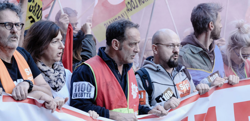 Characters from the film hold up a banner.