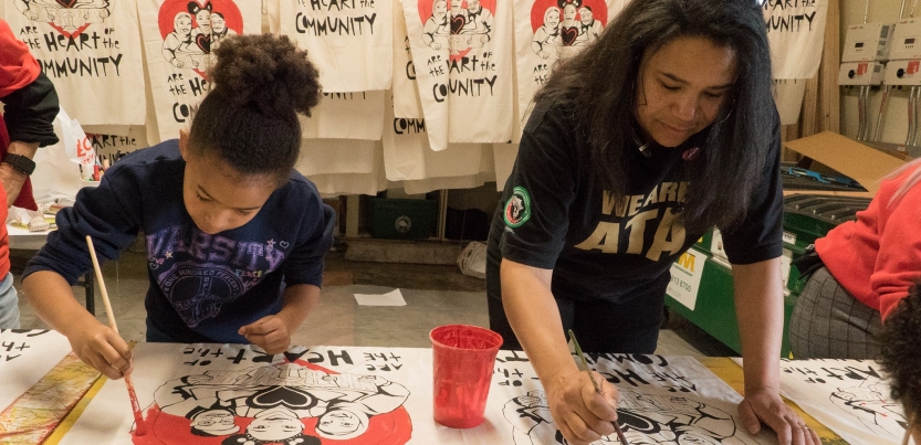 Two people painting signs that say "public schools are the heart of the community"