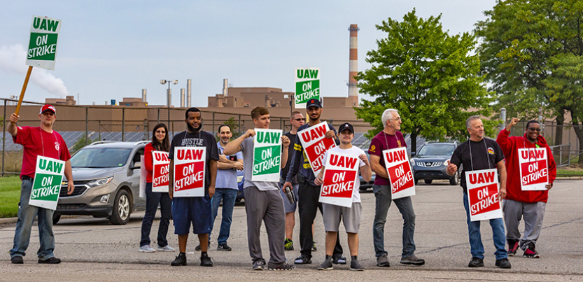 GM strikers picketing on the road holding signs.