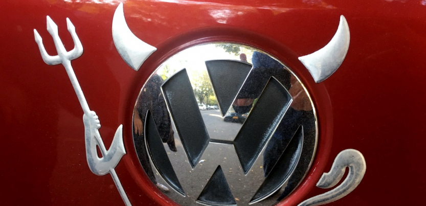 Devil horns, pitchfork, and tail have been added to the VW logo on a car