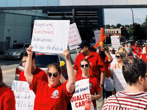 Red-shirted hospital workers march with signs.