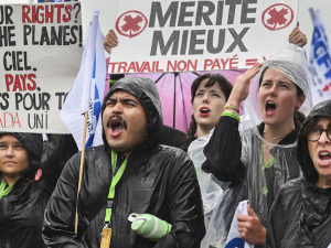 Six picketers hold signs in the rain, including, “Ground our rights? Ground the planes!”