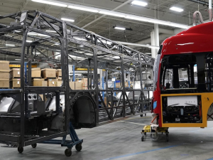The skeleton of an unfinished bus, and the outer shell of another are shown in a factory