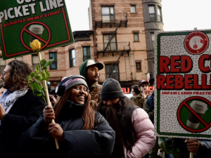 A group rallies holding signs that say Red Cup Rebellion: Unfair Labor Practice Strike, with a Starbucks coffee cup with a red line through it.