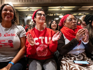Five women sit applauding, one is wearing a CTU T-shirt, another says “we care” with a drawing of a chalkboard