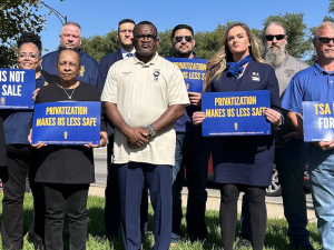 A group stands with signs against privatization of airport security