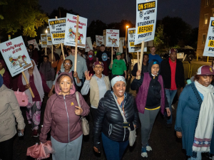 East African workers carrying signs march in the dark during the strike.