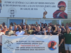 A group of workers hold a banner in front of a French banner. 