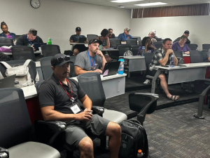Richard, a white man with a mustache and glasses, speaks to attentive labor school participants seated in a classroom.
