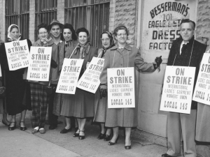 A group of striking garment workers stand in front of their factory in 1958.