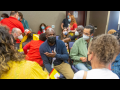 Masked people sit in a circle indoors, talking, in a hotel conference room at the 2022 Labor Notes Conference