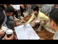 Labor activists on the floor writing with pink marker on a big sheet of white paper.