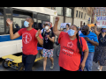 Marchers wearing masks walk through the streets of New York City, with Jabari Brisport and Marcela Mitaynes in the front.