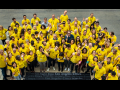 L.A. Times employees gather as NewsGuild members wearing bright yellow shirts around a plaque that says LA Times.