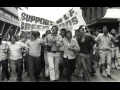 Black and white photo of men marching with a banner: "SUPPORT BLF GREEN BANS"