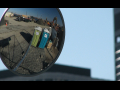 Two portajohns are reflected in a truck side mirror.