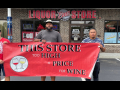 Three workers stand in front of a liquor store holding a banner that reads "This Store Too High a Price for Liquor"
