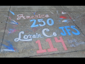 Chalk graffiti on sidewalk says “America 250, Lorain Co. JFS 114 days on strike”